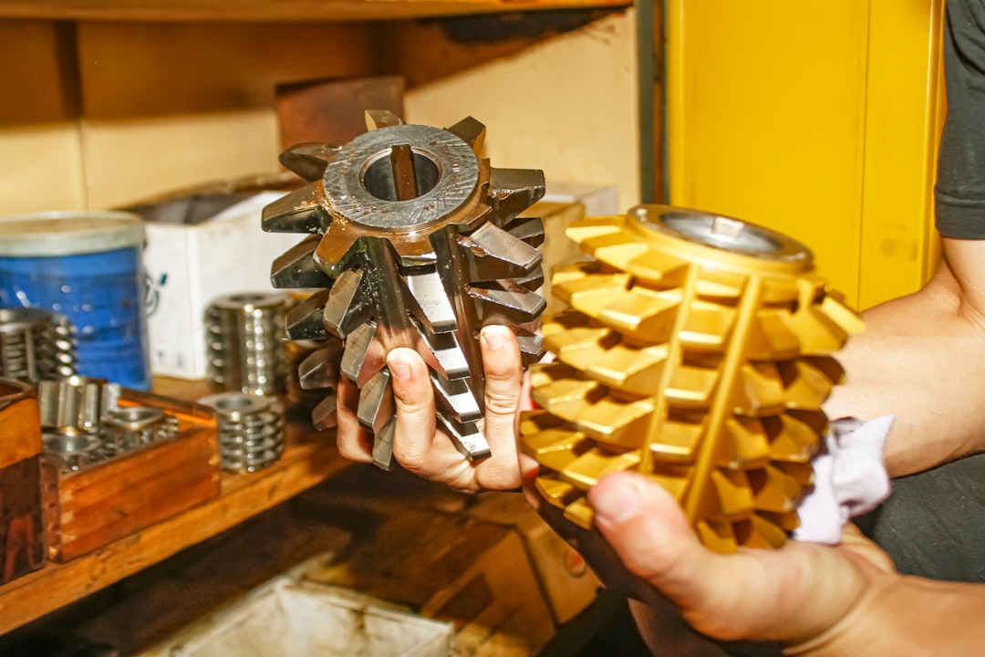 A close-up of an engineer's hands using precise metal calipers to measure a metal cog or gear, symbolizing a technical audit and framework.