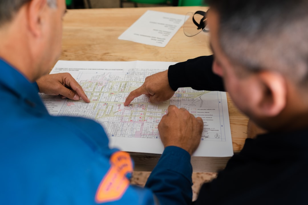 Two frustrated professionals in a modern office look at a complex blueprint, illustrating the communication breakdown and lack of empathy between marketing and development teams.