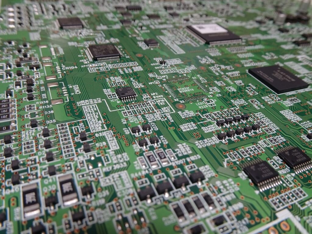 Macro photograph of a chaotic bundle of multi-colored wires being connected to a neat and orderly green circuit board, sym...