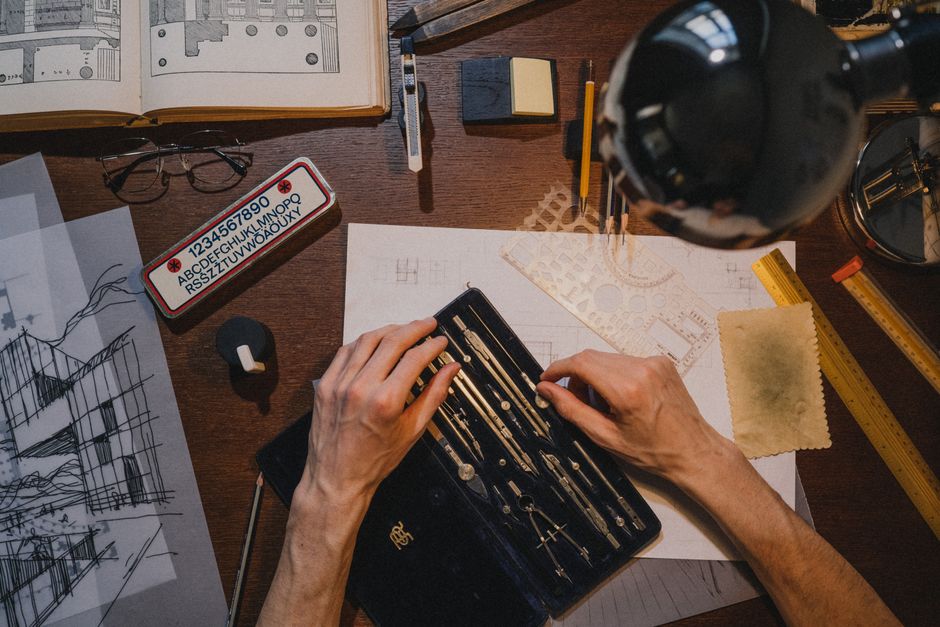 An overhead view of an architect's desk with a detailed blueprint, calipers, and a ruler, representing a precise governance protocol for technical state management.